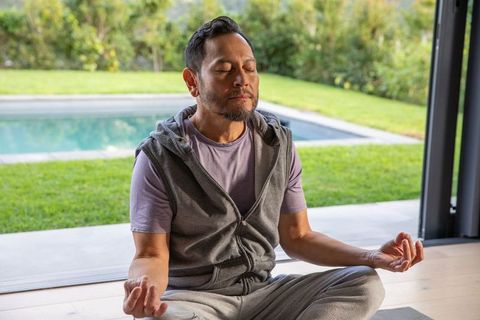 Mature asian man meditating by pool in activewear practicing mindfulness and mudra