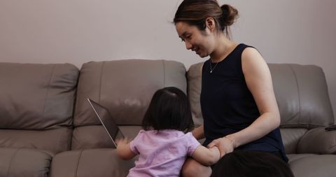 Mother and Daughter Bonding Over Laptop on Couch
