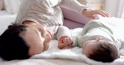 Mother Holding Infant's Hand Lying on Cozy Bed