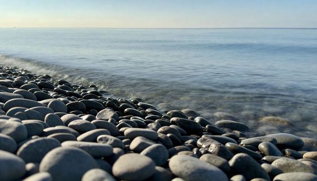Smooth pebble beach with calm sea horizon and glistening wet stones