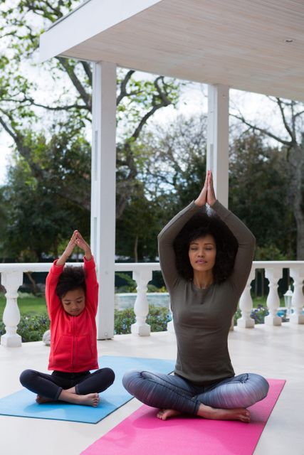 Mother and daughter meditating together in the porch at home