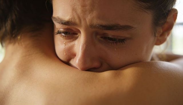 Tearful woman embracing partner seeking comfort and solace during emotional moment