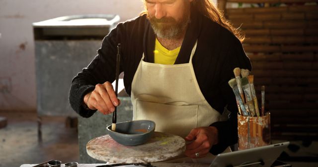 Focused Artisan Painting Pottery in Studio with Brushes and Tools - Download Free Stock Images Pikwizard.com