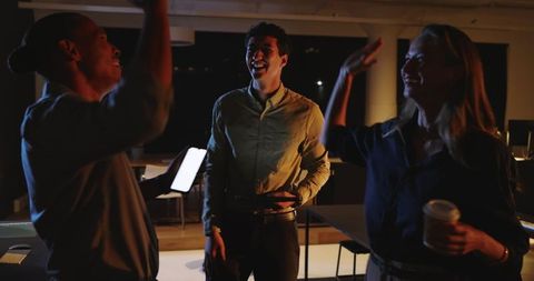 Dynamic Office Team Celebrating Achievement at Night