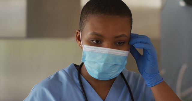African american female doctor taking off face mask breathing deeply. medical healthcare professional at work during coronavirus covid 19 pandemic.