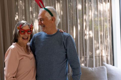 Senior Couple Celebrating Together with Reindeer Antlers in Cozy Home