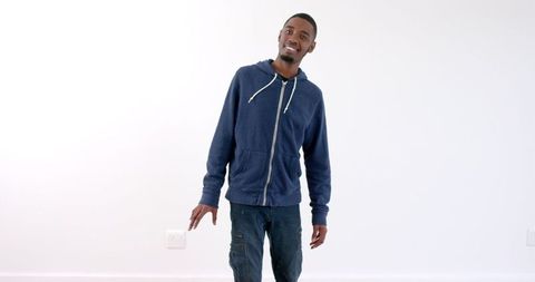 Confident Young Man in Blue Hoodie Walking in Minimalist Setting