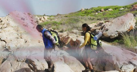 Trekking Partners Explore Rocky Hillside Against Clear Sky
