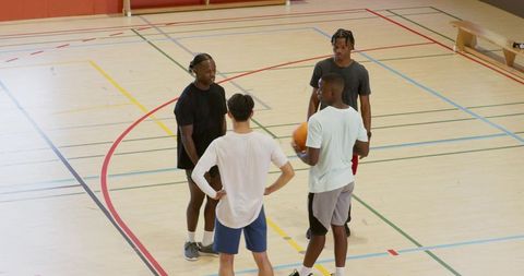 Casual teammates huddling on indoor basketball court discussing strategy