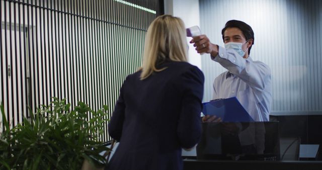 Caucasian businessman wearing face mask checking coworkers temperature - Download Free Stock Photos Pikwizard.com
