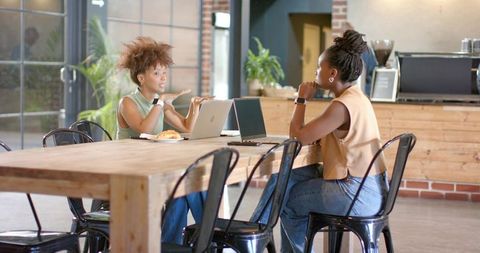 African american entrepreneurs collaborating over laptops in bright urban coffee shop
