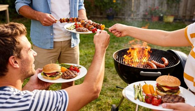 Friends sharing grilled skewers and burgers at sunny backyard barbecue with kettle grill