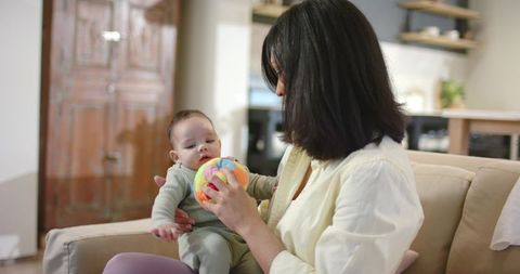 Mother Engaging Baby with Colorful Ball in Cozy Home
