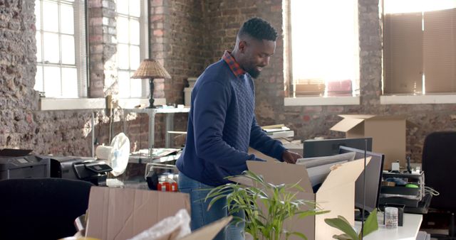 Man Unpacking in Renovated Office Space with Brick Walls - Download Free Stock Images Pikwizard.com