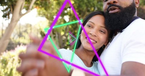 Couple embracing outdoors with neon geometric overlays, romantic park moment