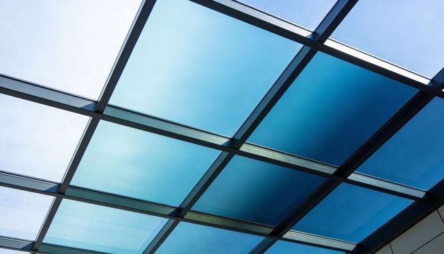Blue glass skylight grid receding in modern atrium with metal mullions and reflections