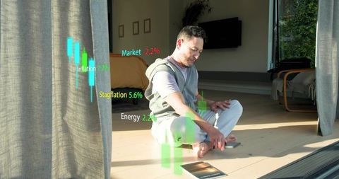 Asian man using ar finance charts at home holding smartphone and tablet holographics