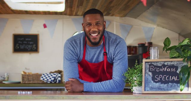 Portrait of african american man wearing apron smiling while standing in the food truck. food truck and street food concept