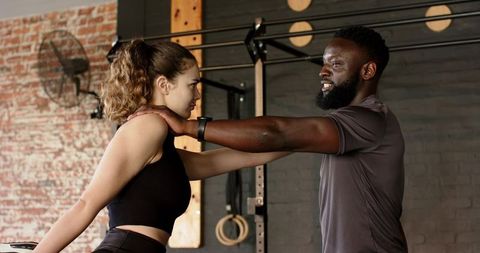 Personal trainer assisting woman with shoulder stretch