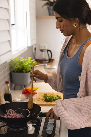 South Asian Woman Cooking Vegetables in Modern Home Kitchen