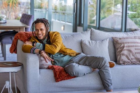 Smiling man reclining on modern sofa in bright open-plan living room