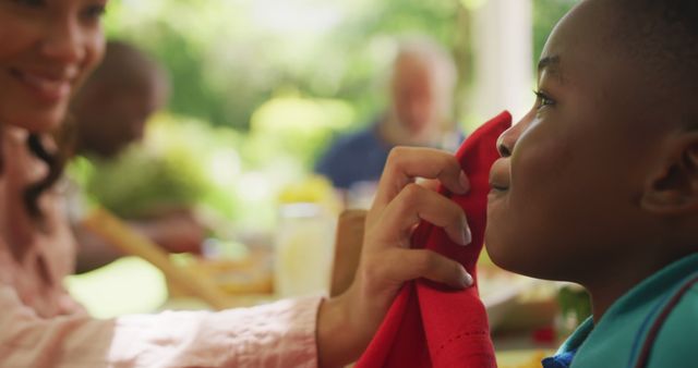 Close-up of caring mother wiping son's face during outdoor family meal - Download Free Stock Images Pikwizard.com