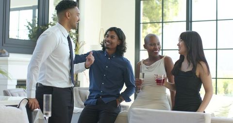 Diverse young professionals chatting over drinks in modern living room