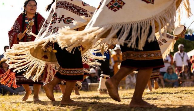 Indigenous north american women dancing with fringed shawls and rattles at outdoor ceremony