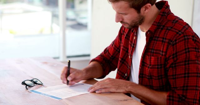 Focused Man Signing Documents in Casual Office Setting - Download Free Stock Images Pikwizard.com