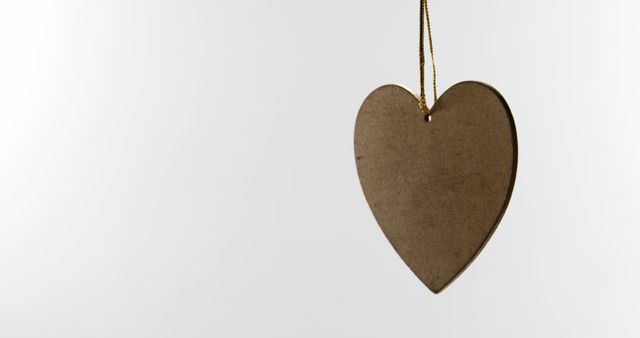 A cardboard heart hangs against a white background, with copy space. Its simplicity suggests a message of love or the concept of eco-friendly, sustainable materials.