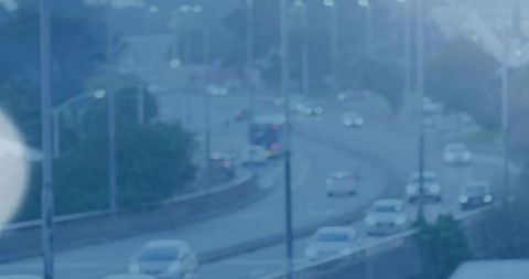 Twilight urban highway curving through cityscape with moving cars and motion-blur lens flare