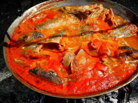 Traditional cooking of spicy fish stew on open flame