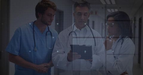 Doctors reviewing tablet in hospital corridor with digital interface overlay