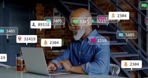 Senior professional typing on laptop in industrial loft receiving digital notifications