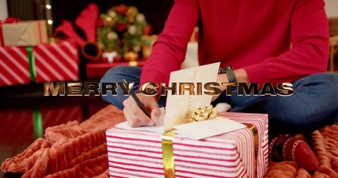 Man writing christmas cards surrounded by festive presents