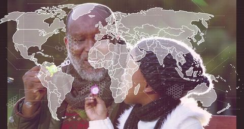 Grandfather and granddaughter blowing bubbles on park bench with world map overlay