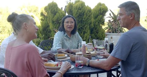 Diverse Friends Enjoying Meal Outdoors on Sunny Patio Gathering