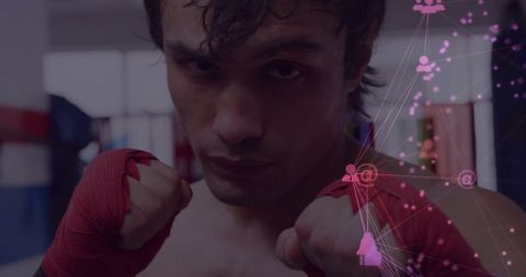 Moody boxer facing camera raising red-wrapped fists with pink digital network overlay
