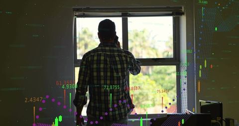 Mid-adult man watching stock market charts on smartphone at sunlit window with overlay