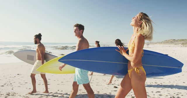 Diverse females and males holding surfboards, laughing and go to the sea at sunset. Summer, having fun, free time, friendship, vacation.