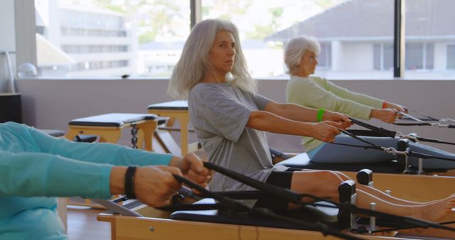 Senior Women Exercising on Pilates Machines in Bright Fitness Studio - Download Free Stock Images Pikwizard.com