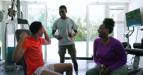 Energetic personal trainer motivating young couple at home gym