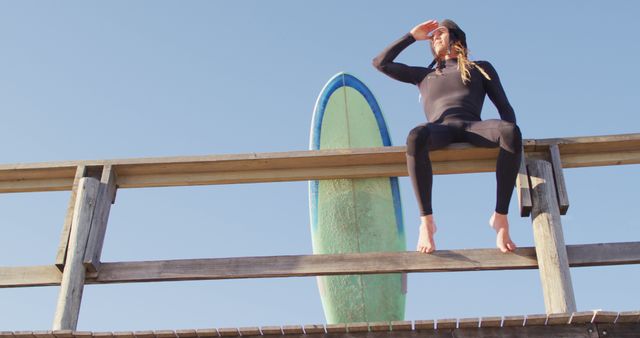 Female Surfer Sitting on Fence with Surfboard Enjoying Ocean View - Download Free Stock Images Pikwizard.com