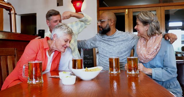 Middle-aged friends sitting at a pub table, enjoying drinks and having fun. They appear to be in a celebratory mood, sharing laughs over beers and snacks. Ideal for content on social gatherings, friendship, leisure activities, and diverse communities.