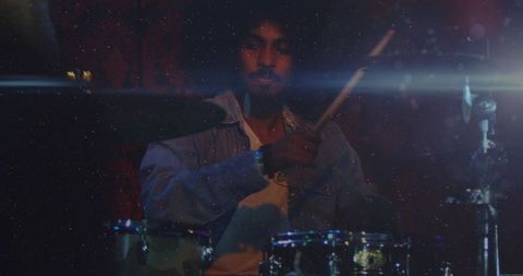Drummer playing on dimly lit stage with atmospheric lighting