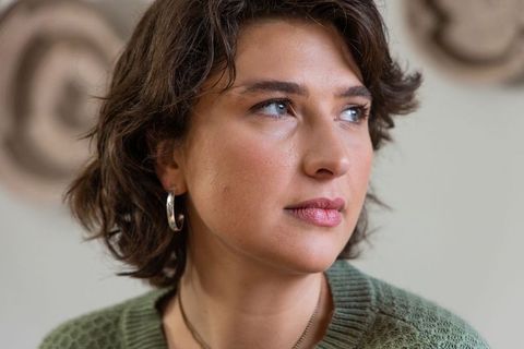 Contemplative woman gazazing right wearing green sweater and silver hoop earrings closeup
