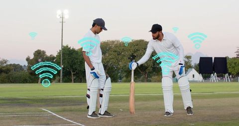 Cricket team practicing at dusk adjusting bat grip under floodlights with wifi overlays