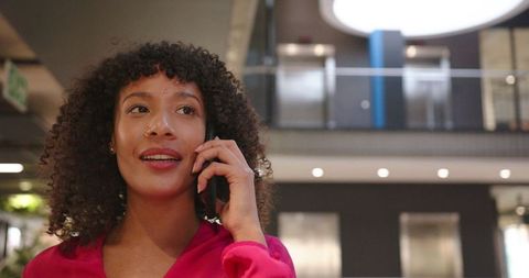 Businesswoman in office lobby talking on smartphone confidently