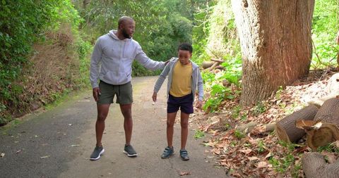 African american father guiding son on sunlit forest trail for family bonding