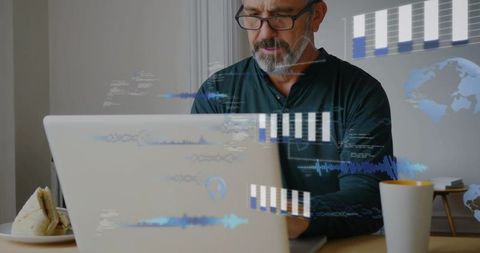 Mature man working on laptop analyzing digital data overlays in minimalist home workspace